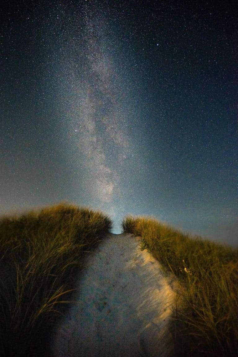 A path through fields aligns with the light of the starry night sky