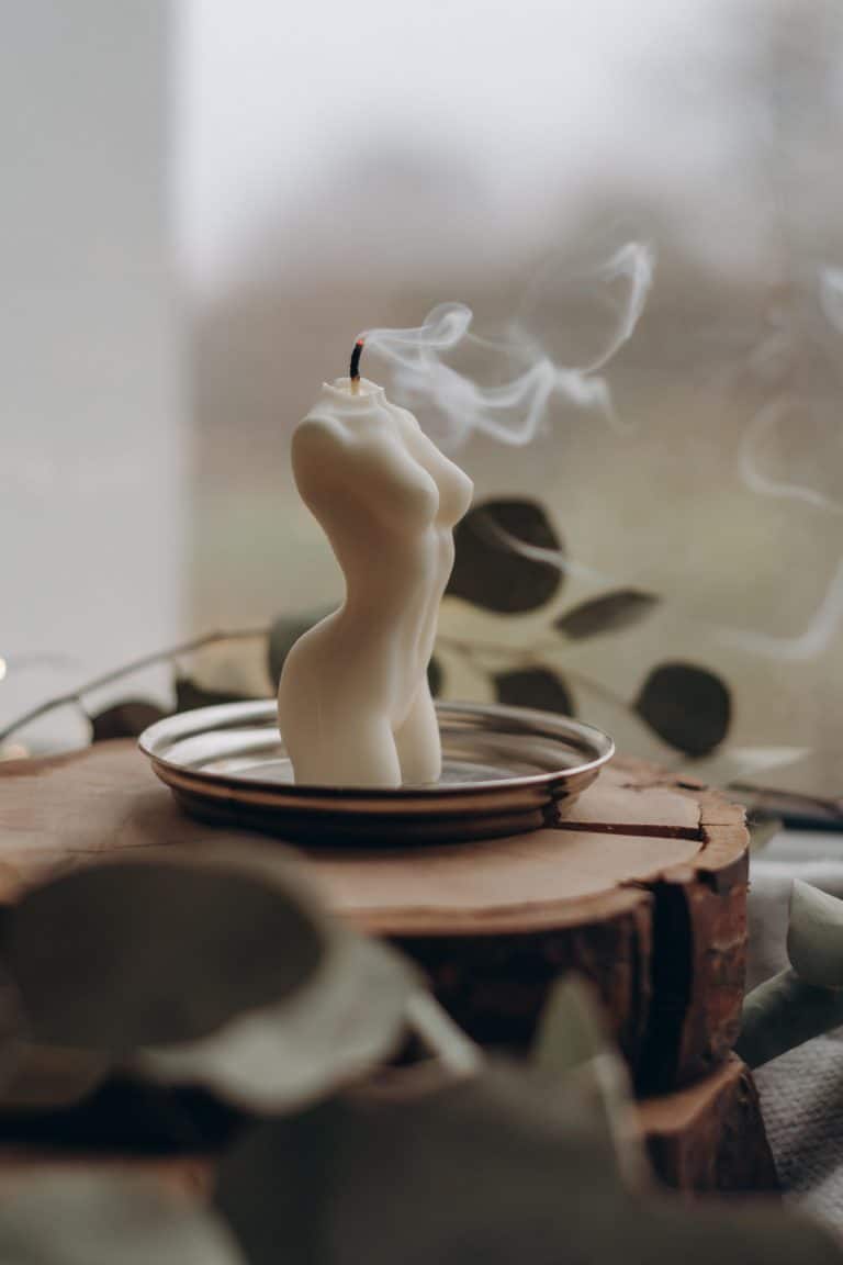 A candle of an upper body has been burned down past the head and extinguished; smoke floats away